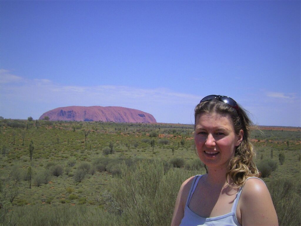 Frau in Australien vor dem Ayers Rock. Viel blauer Himmel