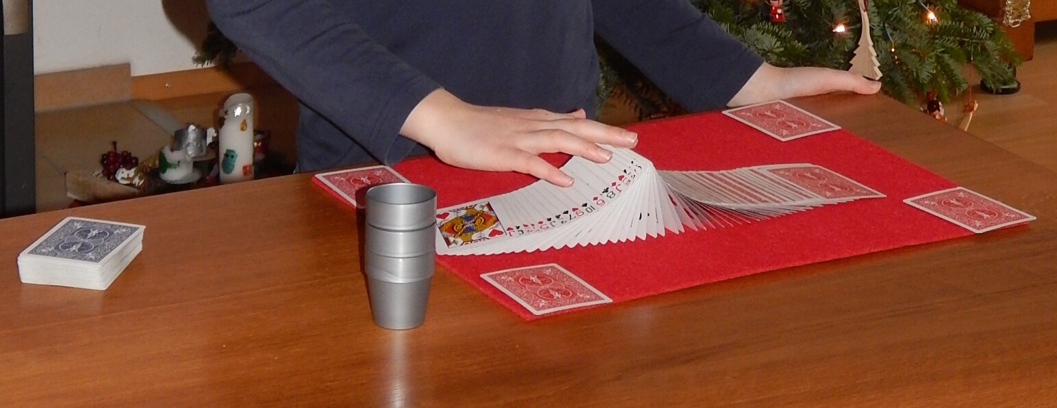 Ein Kind zaubert. Man sieht nur die Hände und Karten auf dem Tisch.