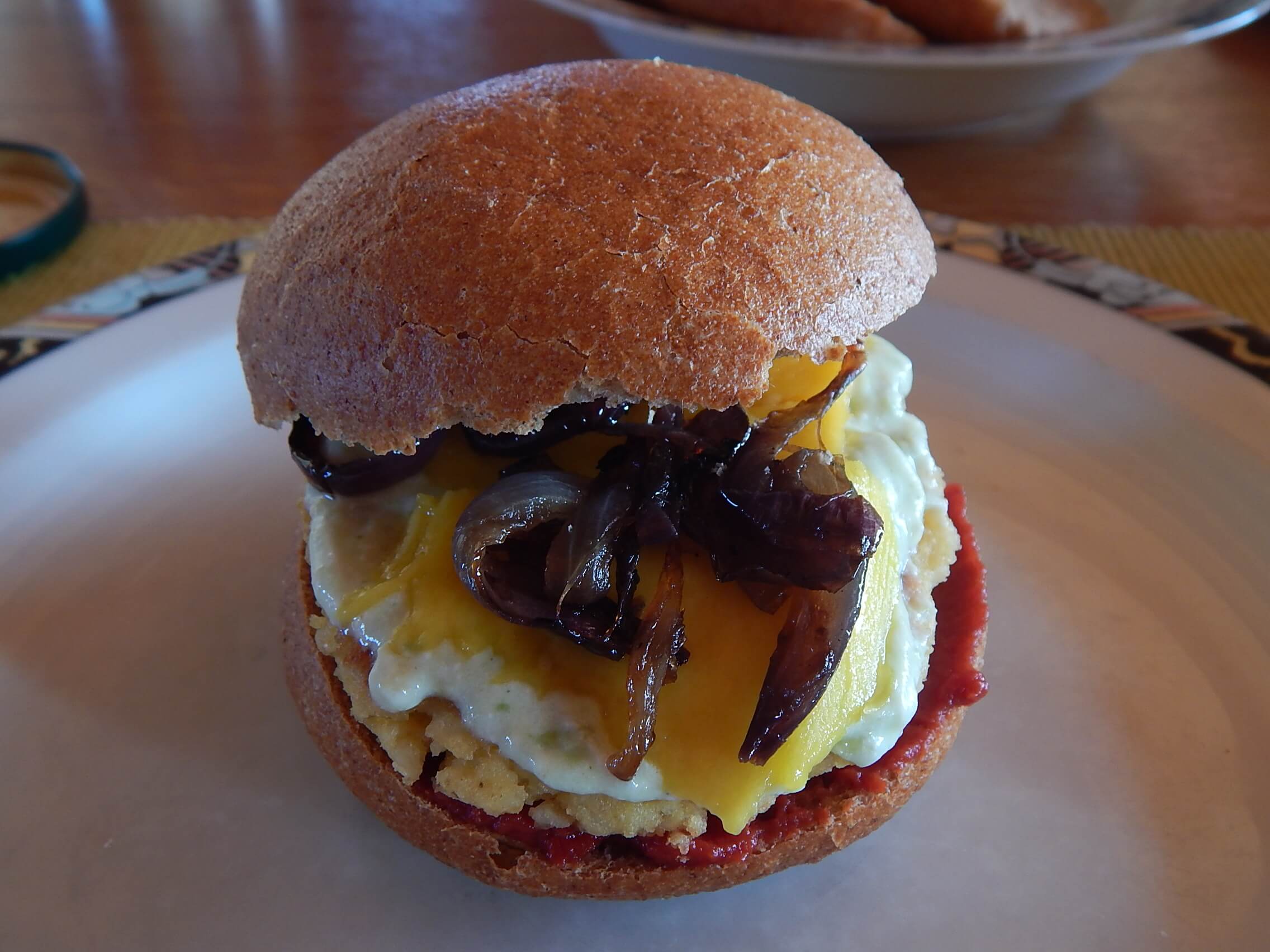 Ein Hirseburger auf einem Teller. Sehr lecker mit Mango und Zwiebeln .