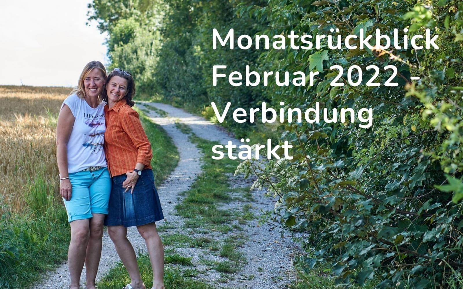 Header für den Blogartikel: Ein Waldweg, zwei Frauen umarmen sich. Überschrift: Monatsrückblick Februar 2022 - Verbindung stärkt